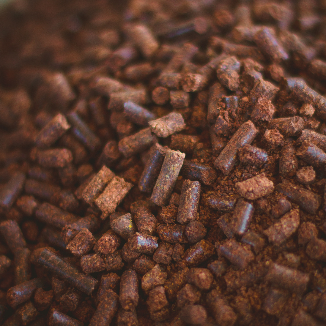 Close-up of Smokin' Pecan Shell Pellets - 2 lb Bag shows brown, cylindrical, irregular pellets with a rough texture and earthy look, resembling eco-friendly fuel.