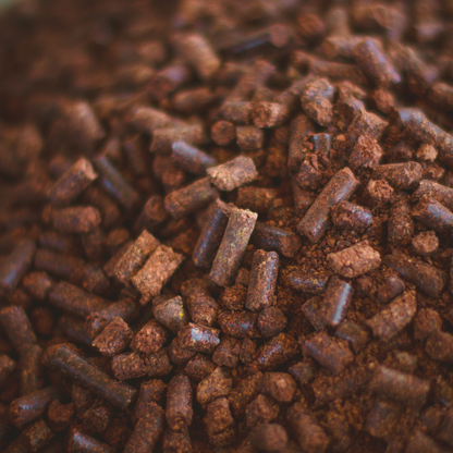Close-up of Smokin' Pecan Shell Pellets - 2 lb Bag shows brown, cylindrical, irregular pellets with a rough texture and earthy look, resembling eco-friendly fuel.