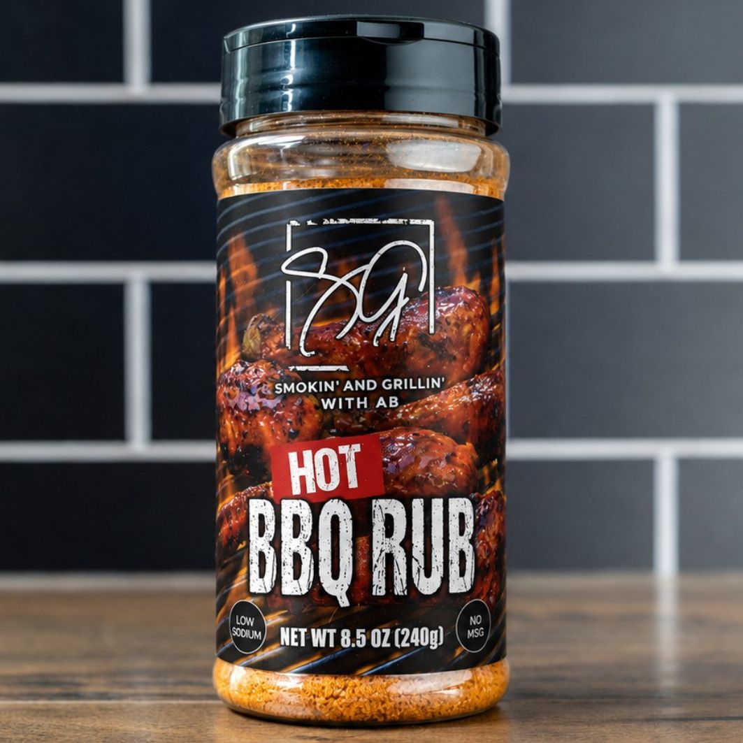 A jar of AB's Hot BBQ Rub by Smokin and Grillin wit AB rests on a wooden surface before black tiles. The label displays grilled meat with bold white and red text, highlighting the smoky, spicy flavor of this barbecue seasoning.