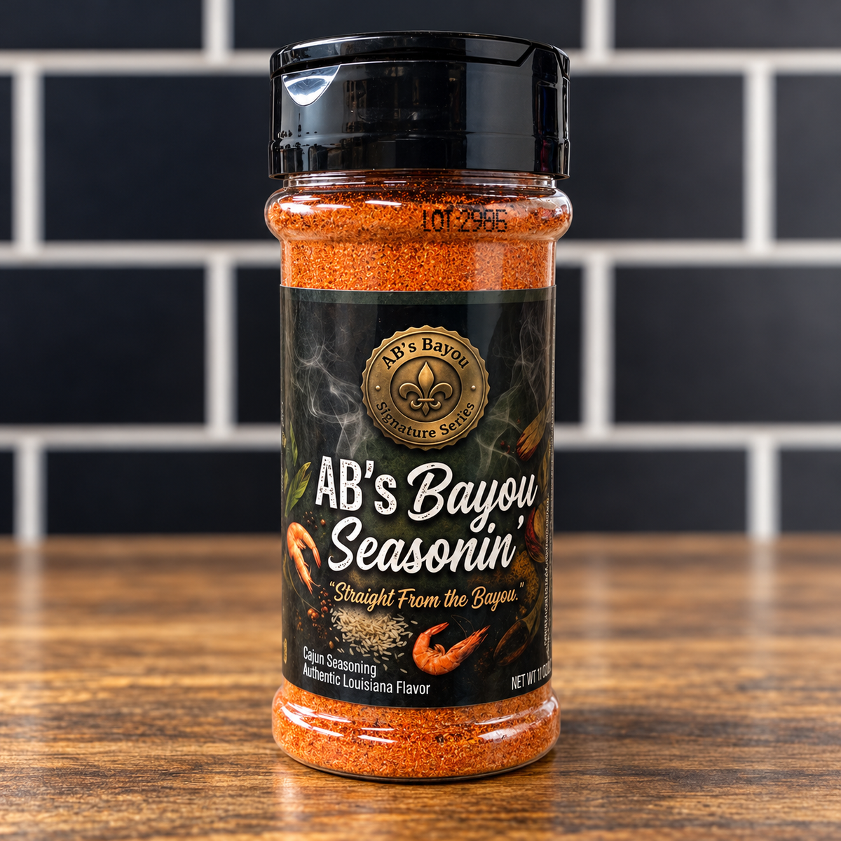 A clear plastic shaker bottle of AB’s Bayou Seasonin’ featuring a black label with an emblem, text, and graphics of shrimp and rice.