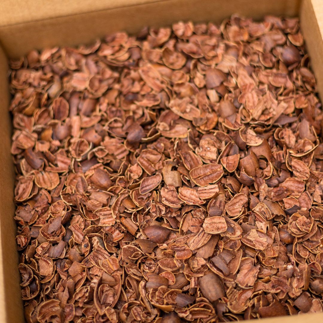 A close-up view of a 17 lb box of Smokin' Pecan Shells, perfect for use as a unique BBQ fuel or smoking meat, similar to how cocoa bean shells are used during chocolate production.
